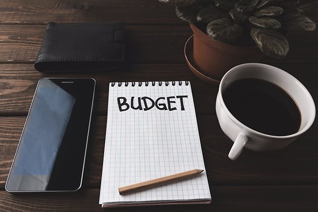 Notebook on a table with a cup of coffee for writing out a vinyl flooring budget