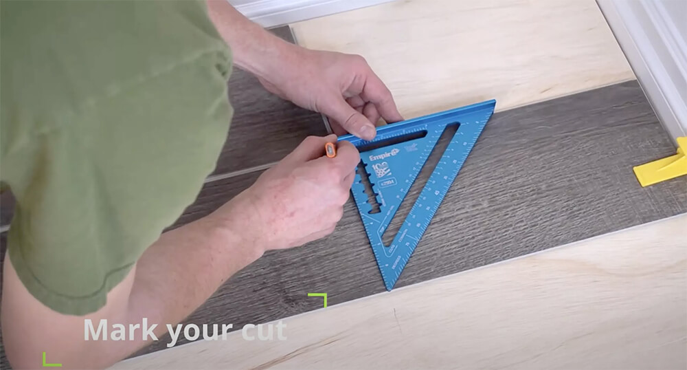 Person marking a cut line on a luxury vinyl plank