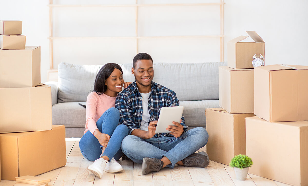 Millennial couple sitting between boxes in their new apartment