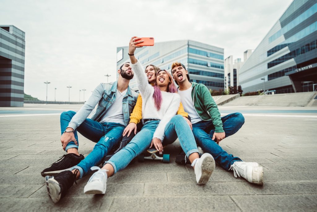 Group of young people taking selfies in front of apartments