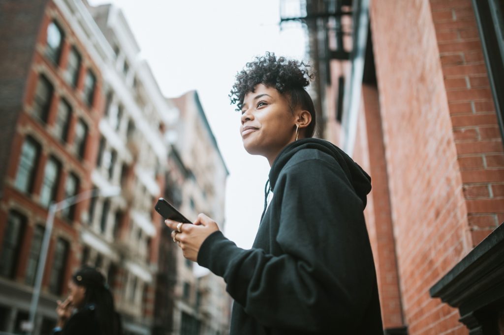 Woman smiling on the street in front of apartment buildings