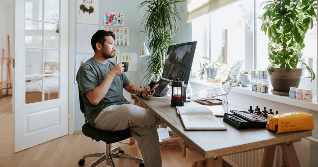 Man drinking coffee while working remotely in his condo