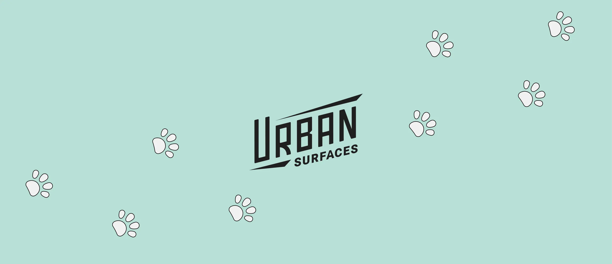 Urban Surfaces logo in the midst of Paw Prints on a green background.