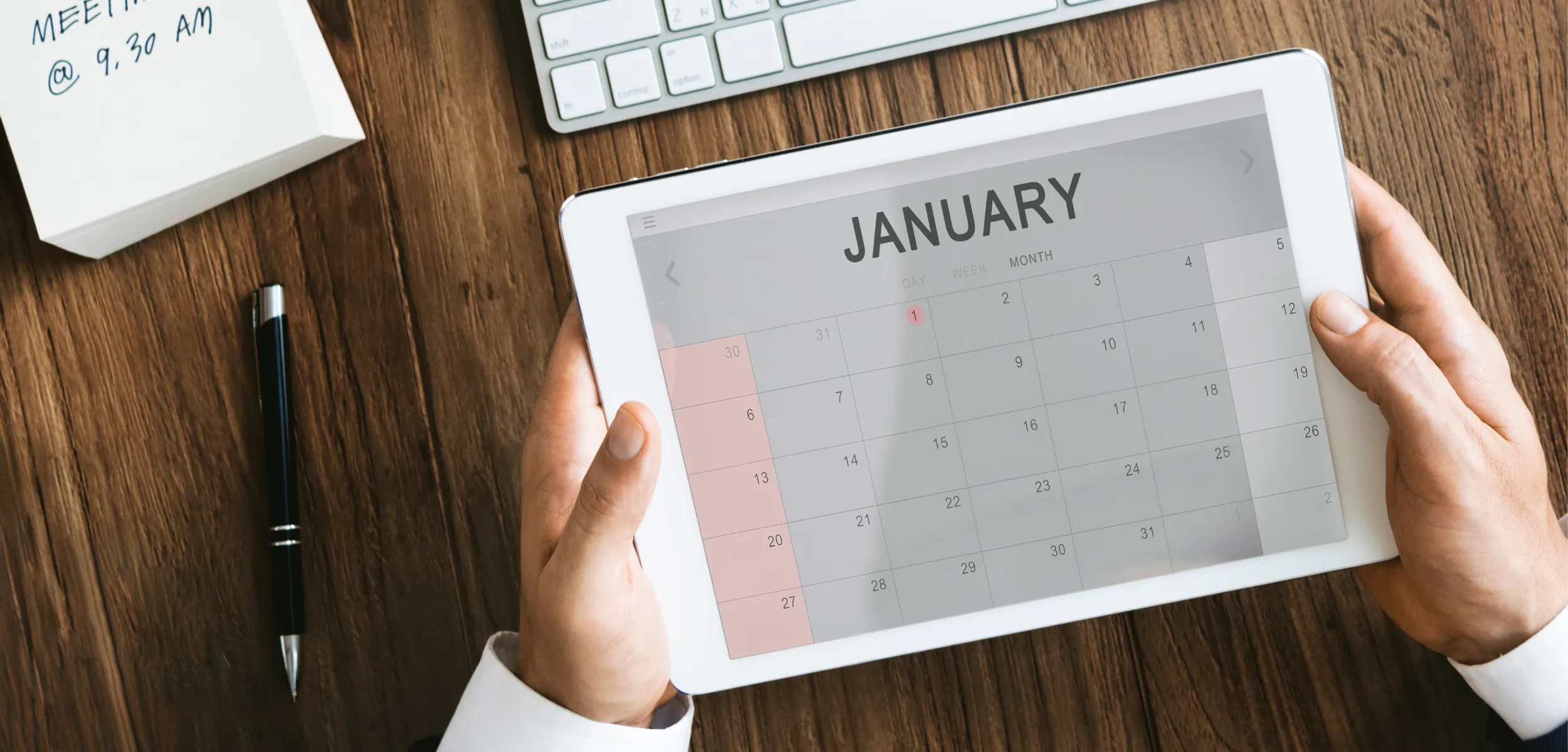 Person holding an iPad looking at a calendar.